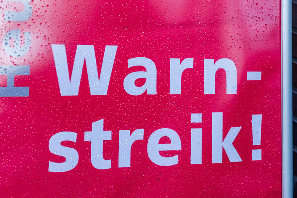 Bild vergrößern: Transparent zum Streikaufruf bei regnerischem Wetter
